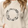 A floral design made up of intertwined leaves and flowers forming a circular shape.