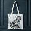 A sitting big cat with distinctive markings and a bushy tail, typical of the wild animal species known as the ocelot.