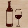 A glass filled with red wine on a table, next to a bottle.