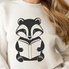 A wildlife illustration of a badger sitting on the ground with an open book in front of it.